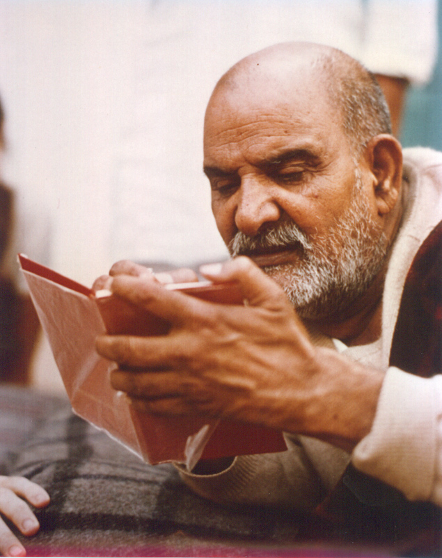 Neem Karoli Baba wrapped in his plaid blanket, reading